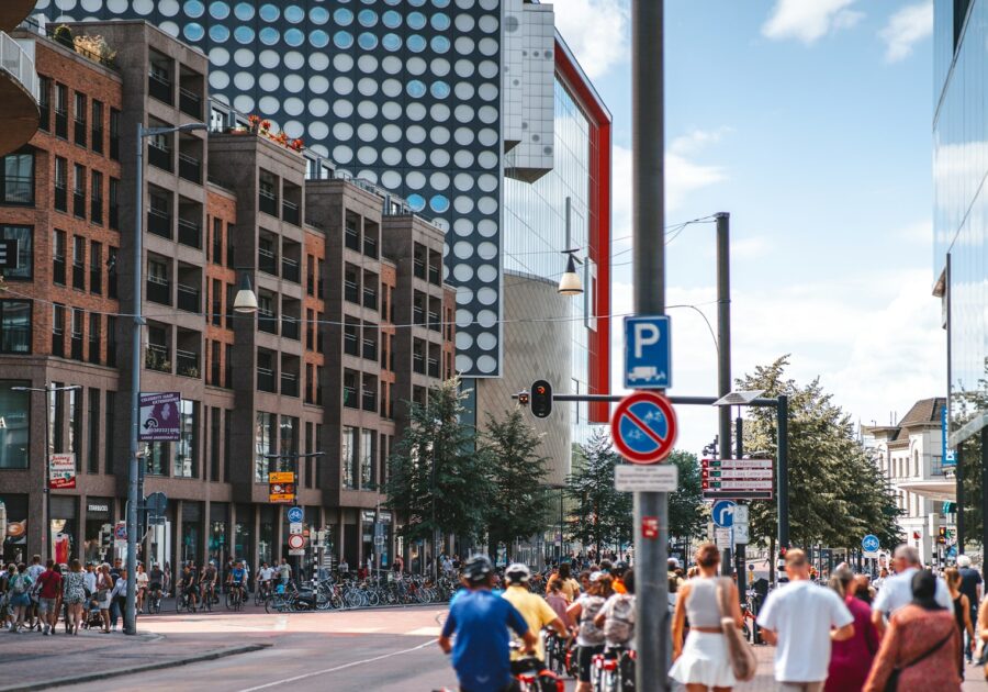 a group of people walking down a street next to tall buildings