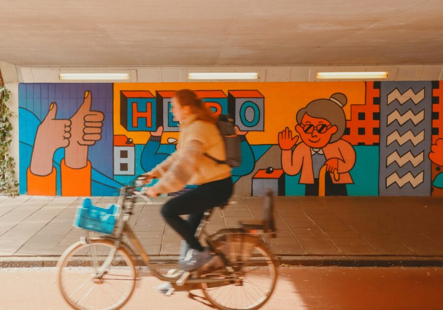 a woman riding a bike in front of a colorful wall
