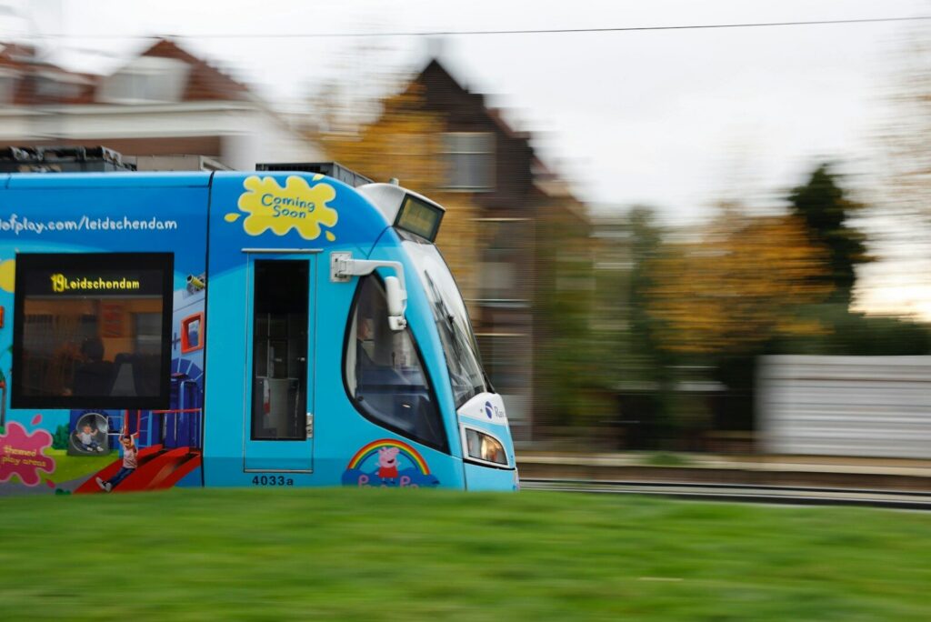 a blue bus driving down a street next to a lush green field
